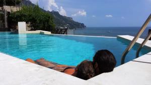 拉维罗Pagliarulo Complex by AMALFIVACATION的坐在游泳池里看海洋的男人和女人
