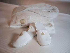 多哈Pullman Doha West Bay的床上一双白色的拖鞋和一条毛巾