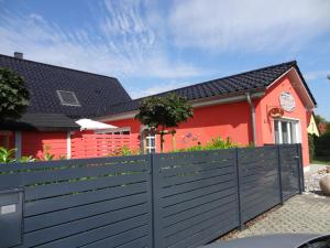 LoissinFerienhaus Loissin的前面有黑色栅栏的红色房子