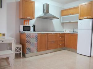 厄尔梅达诺Apartmento La Perla el Medano的厨房配有木制橱柜和白色冰箱。