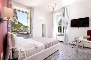 阿马尔菲Valle d'Amalfi Suites的白色的客房设有床、桌子和窗户。