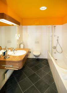 米尔茨楚施拉格温克勒酒店及餐厅的一间带水槽、浴缸和卫生间的浴室