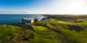 赫尔努姆BUDERSAND Hotel - Golf & Spa - Sylt的享有毗邻大海的高尔夫球场的空中景致