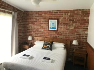 Waratah Bay舞会海岸度假别墅的一间卧室设有一张床和砖墙