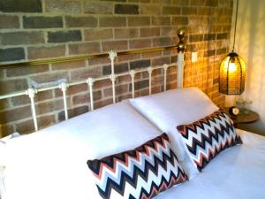 泰克利绿人精品酒店的一张带两个枕头的床,墙上有砖墙