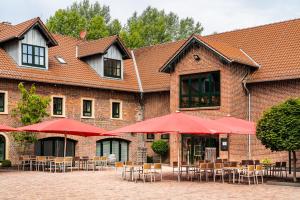 GensingenClassicX Landhaus & Hotel - Bed & Breakfast的一座配有桌椅和红色遮阳伞的建筑