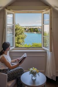 扎达尔堡垒遗产酒店 - 休闲城堡的女人在窗前读书