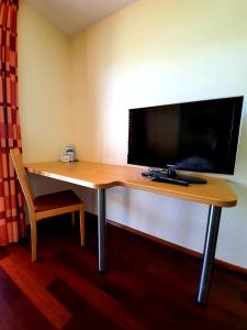 霍赫斯特加尔尼戴斯睿智酒店的一张位于酒店客房内的桌子,配有电视和笔记本电脑