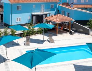 CojaVilla Montês Guesthouse的一个带遮阳伞和椅子的游泳池以及一座蓝色建筑