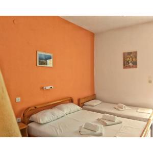 RizáArtolithia Apartments的橙色墙壁客房的两张床