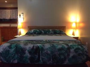 阿鲁坦加艾图塔基海边山林小屋的卧室内的一张大床,配有两盏灯