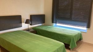 ConceiçãoFranciscos em Cabanas Golf的带窗户的客房内的两张绿色床