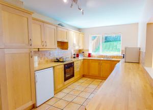 邓莫尔东Fishermans Grove 3 Bed的厨房配有木制橱柜和白色冰箱。