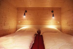 齐罗Schwarzes Holzferienhaus mit Sauna -- L I E B L I N G S P L A T Z -- an der Ostsee, Zierow bei Wismar, Strand 500m, alles inklusive的配有木墙和灯的客房内的两张床