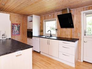 格隆霍6 person holiday home in L kken的厨房配有白色橱柜和黑色台面