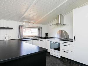 瓦伊厄斯斯特兰德8 person holiday home in Vejers Strand的厨房配有白色橱柜和黑色台面