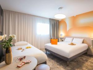佩尔蒂ibis Styles Pertuis Portes du Luberon的酒店客房设有两张床和一张桌子。