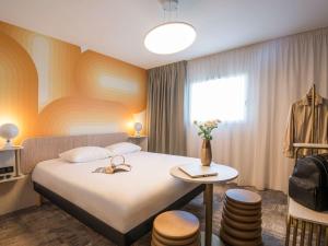 佩尔蒂ibis Styles Pertuis Portes du Luberon的酒店客房设有床、桌子和窗户。