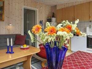 瓦伊厄斯斯特兰德4 person holiday home in Vejers Strand的一张桌子上满是橙色和白色花的蓝色花瓶
