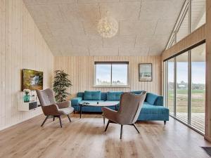 瓦伊比18 person holiday home in Vejby的客厅配有蓝色的沙发和两把椅子