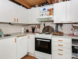 Kolind7 person holiday home in Kolind的厨房配有白色橱柜和炉灶烤箱。