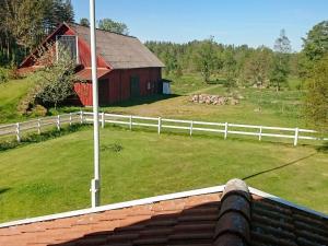 Karrum5 person holiday home in GAMLEBY的享有农场的景色,农场设有白色的围栏和红色的谷仓