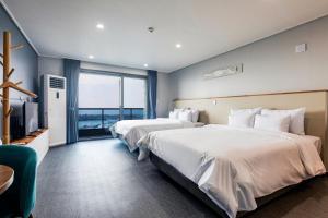 济州市Aewol Stay in Jeju Hotel&Resort的酒店客房设有两张床和电视。