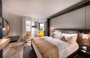 诺伊斯Crowne Plaza Düsseldorf - Neuss, ein IHG Hotel的酒店客房设有一张大床和一张黄色椅子