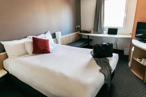 纽卡斯尔纽卡斯尔宜必思酒店的酒店客房配有一张带红色枕头的大型白色床。