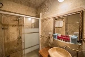 格雷梅Charming Cave Hotel的浴室配有盥洗盆和带镜子的淋浴