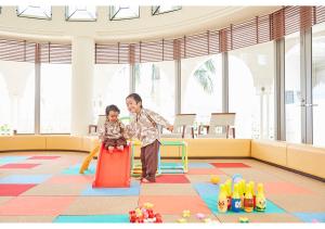本部冲绳马海纳健康度假酒店的男人和小女孩在操场上玩耍