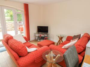 PontyclunNuthatch Barn的客厅配有红色的沙发和桌子