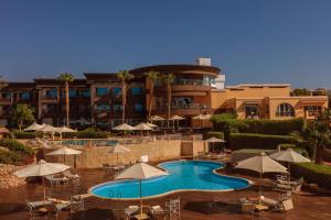 沙姆沙伊赫Royal Savoy Sharm El Sheikh的一个带椅子和遮阳伞的游泳池的度假酒店