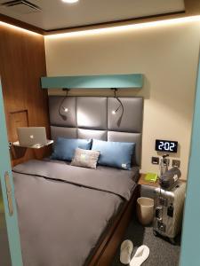 多哈sleep 'n fly Sleep Lounge, SOUTH Node - TRANSIT ONLY的一间卧室配有一张带蓝色枕头的床和一台笔记本电脑
