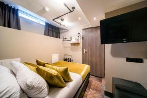 阿姆斯特丹阿尔弗雷德酒店的一间卧室配有一张带金色枕头的床和一台平面电视。