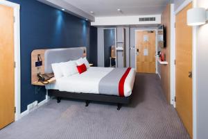 利兹利兹市中心军械库智选假日酒店的一间卧室设有一张床和蓝色的墙壁
