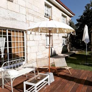 Santa Cristina de CobresOs Areeiros Turismo Rural & Bodega的庭院配有两把椅子、一把遮阳伞和一张桌子