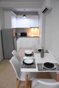 地拉那Click Apartments - Tirana的一间带桌子和白色椅子的厨房以及一间配有冰箱的厨房