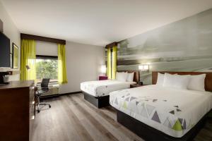 布拉塞尔顿La Quinta Inn & Suites by Wyndham Braselton的酒店客房配有两张床和一张书桌