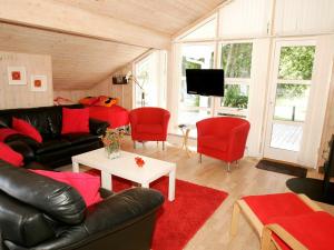 维斯特索马肯8 person holiday home in Aakirkeby的客厅配有黑色真皮沙发和红色椅子