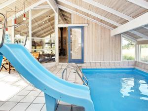 莱斯8 person holiday home in L s的一座房子里一个带蓝色滑梯的游泳池