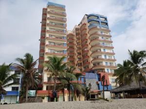 阿塔卡梅斯Arco Iris Atacames的海滩上一座高大的棕榈树建筑