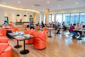 素叻兰花江景酒店的一间设有橙色椅子的餐厅,有坐在桌子上的人