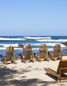 塔马林多Sueño del Mar Beachfront Hotel的一组椅子坐在海滩上