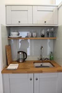 PaulBryher Cottage的厨房柜台配有水槽和白色橱柜