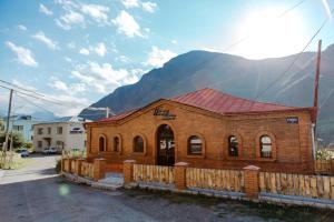 卡兹贝吉Home Kazbegi的山前有栅栏的砖砌建筑