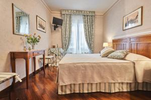 佛罗伦萨乐坎德拉邱比酒店的一间卧室配有一张床、一张书桌和一个窗户。
