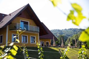 韦因地区拉奇Weingut-Gästezimmer UHL的黄色房子的一侧设有阳台