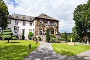Burgbrohl布尔格布罗尔施劳斯酒店的一座带草地庭院的大型石屋