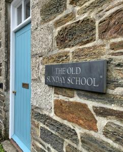 赫尔斯顿The Old Sunday School的一块砖砌建筑的一边,有蓝色门的标志